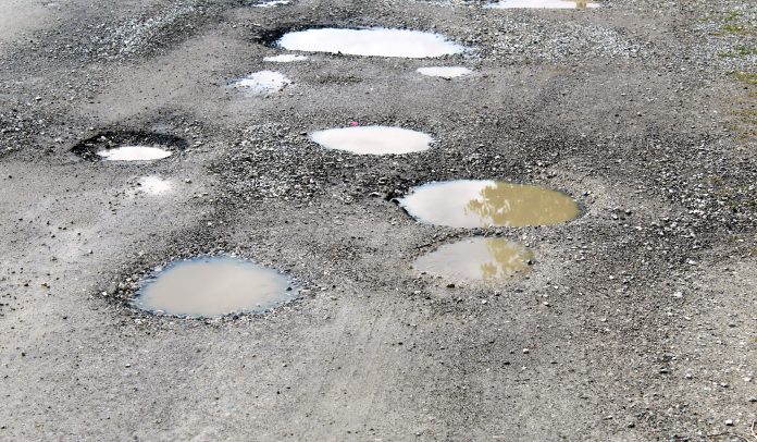 Potholes filled by water on a rural unpaved road pothole repair,