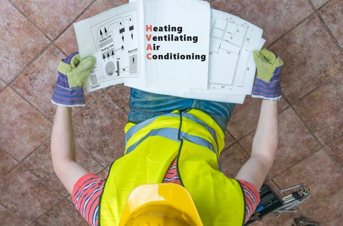 Plumber is looking at documentation of HVAC (Heating, Ventilatin smart connected HVAC, BSRIA,