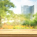 Empty of wood table top on blur of fresh green garden with city