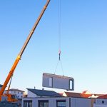 assembly of a prefabricated house, crane lifting a wall componen