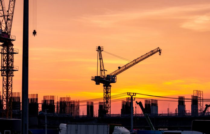 Construction site with crane and sunset sky. Real estate industr Construction Product Information Survey, hackitt review