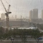 A crane in heavy rain is working on building a skyscraper