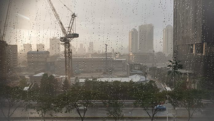 A crane in heavy rain is working on building a skyscraper climate experts,