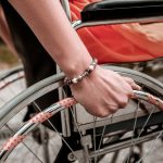 Person with disability sitting in the wheelchair and putting hand on the wheel