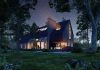 modern designed house at night lit up with greenery surrounding property