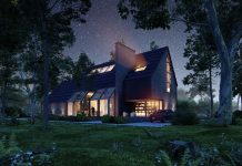 modern designed house at night lit up with greenery surrounding property