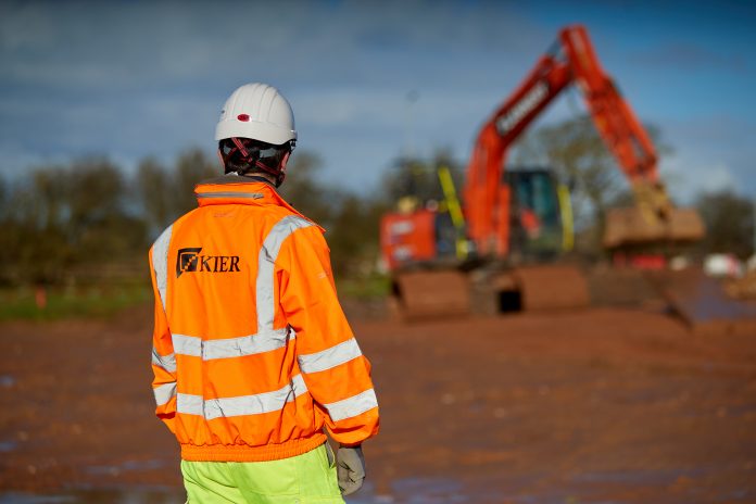 Kier employee in full PPE standing in front of a digger at the A585 Windy Harbour to Skippool improvement scheme