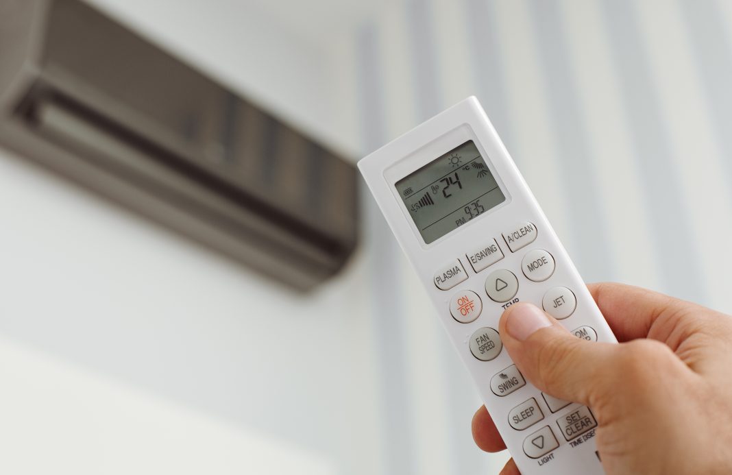 dreamstime_xxl_140868251 close up of man turning up air conditioning in home