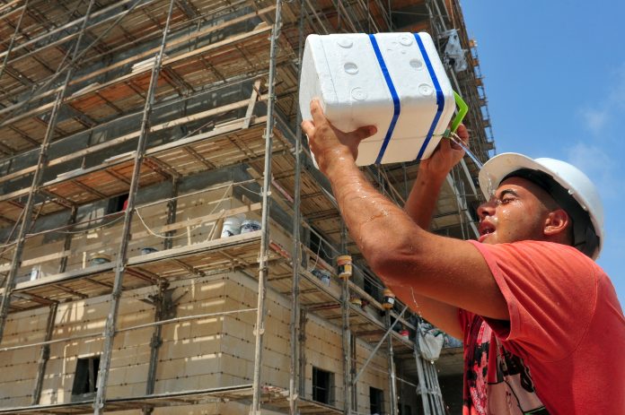construction worker pouring water on himself during a heatwave when it is too hot to work