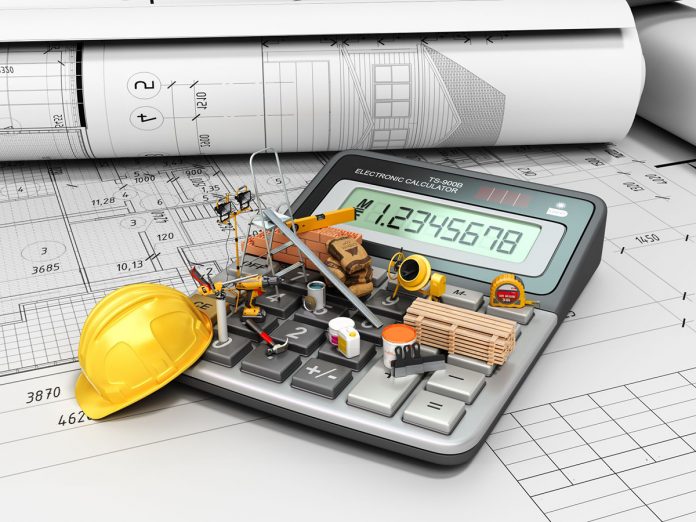 miniature construction equipment on top of calculator used for self build construction blue print plans