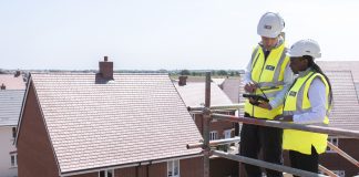 NHBC workers stood on scaffolding overlooking new build housing site