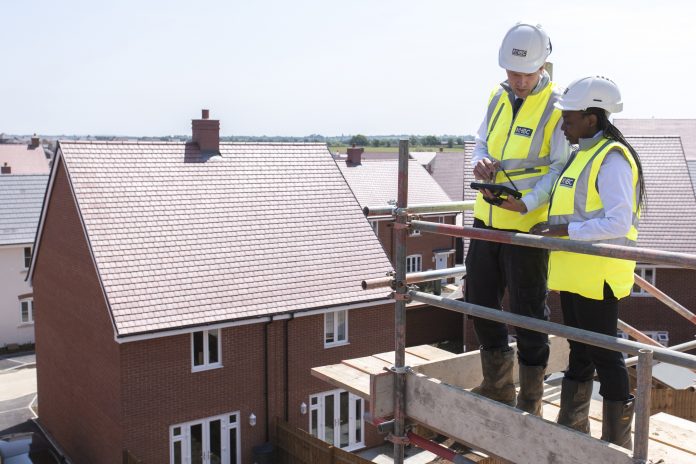NHBC workers stood on scaffolding overlooking new build housing site