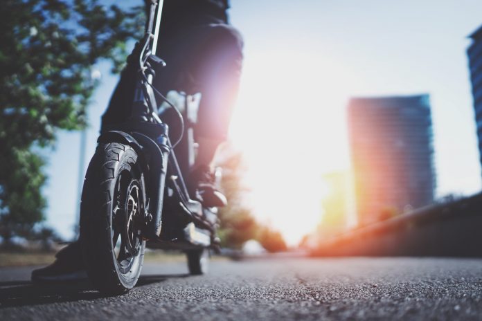 photo of person riding electric scooter on road