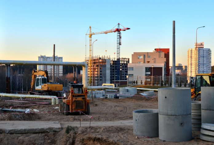 Large construction site with working cranes and heavy machinery for road works, wheel loader, bulldozer, excavator