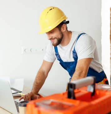 construction worker typing up e-invoice on laptop after job
