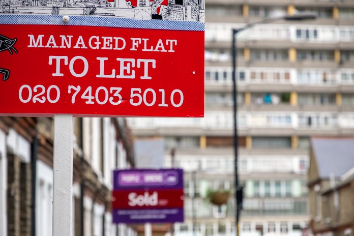 TO LET and sold sign displayed on London street with a council tower block in Aylesbury Estate in the background, right to buy policy