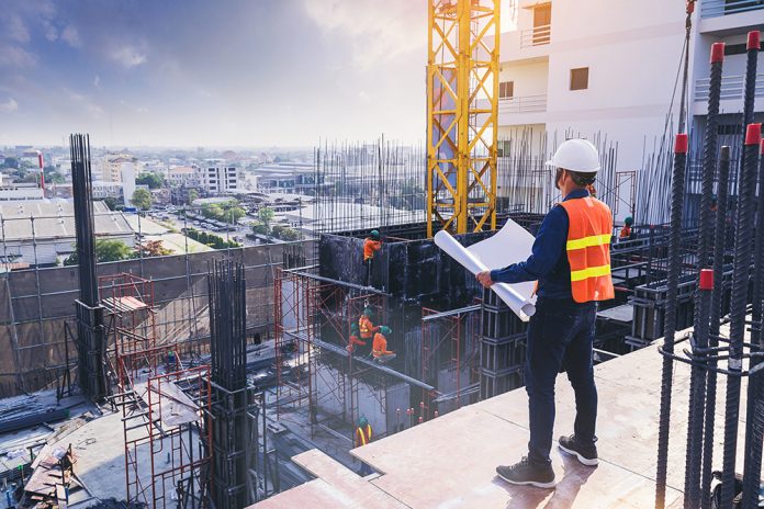 Smart civil architect engineer inspecting and working outdoors building side with blueprints. engineering and architecture concept.