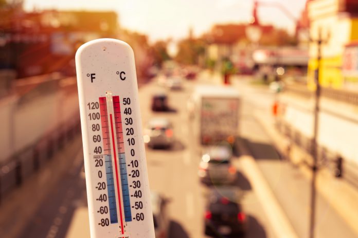 thermometer with moving traffic in background - concept of the effects of extreme weather on the UK's vital infrastructure