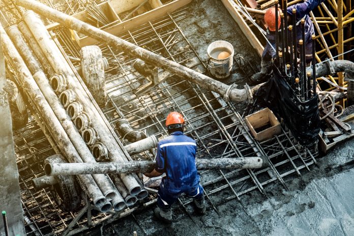 Construction workers wear protective clothing and yellow helmets