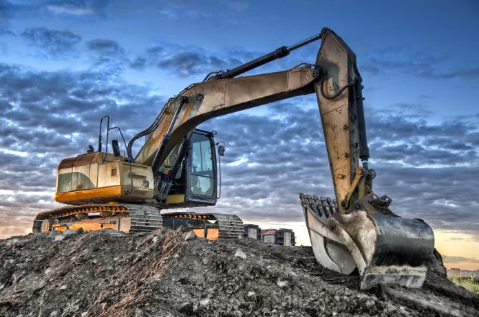 Image shows an excavator against a cloudy blue sky background- the type of vehicle that crushed worker Shannon Brasier