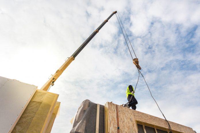 dreamstime_xxl_84428099 Roofer builder worker with crane installing modular structural Insulated Panels SIP