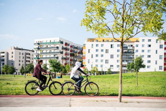 two people cycling in front of sustainable development buildings surrounded by greenery