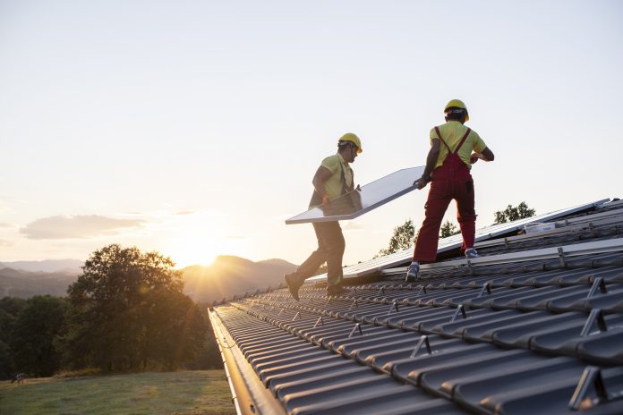 Shot of technicians installing solar panels on a roof, sustainable construction trends