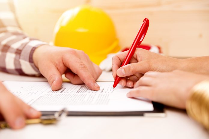Woman signing construction contract with contractor to build a house - construction project insurance