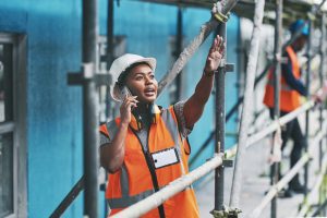 Shot of a young woman talking on a cellphone while working at a construction site