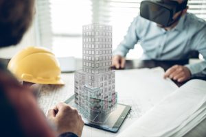 Male Architect wearing augmented reality headsets looking at the virtual model of his project. He has a coordination meeting to present the project