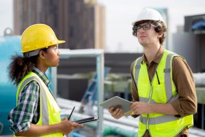 Young man and woman is architect planning and inspector project and looking digital tablet at construction site, engineer male and female working and examining for development real estate.