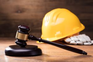 Judge Gavel In Front Of Yellow Safety Helmet On The Wooden Table