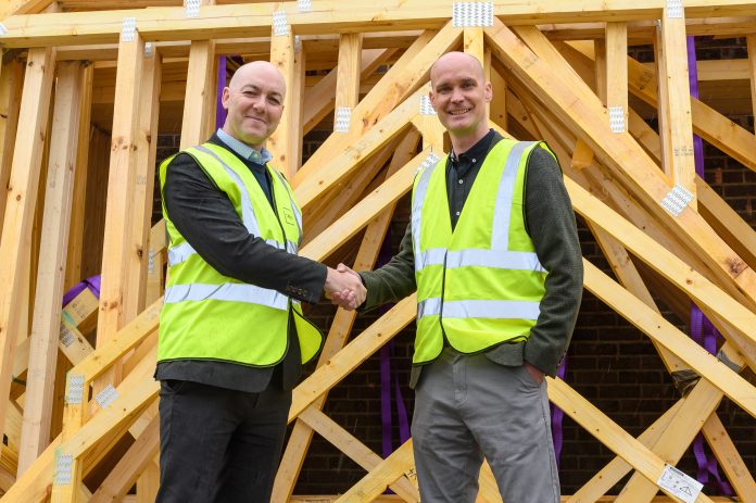 Image of two men shaking hands in front of timber frame