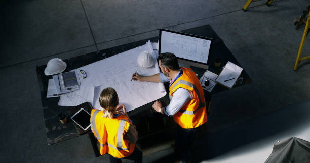 How to ensure sustainability in infrastructure: Best practice for project success High angle shot of two engineers going over a blueprint together in an industrial place of work representing sustainability in infrastructure
