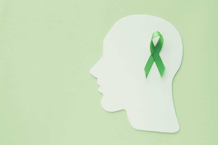 brain paper cutout with green ribbon on green background, mental health concept, world mental health day