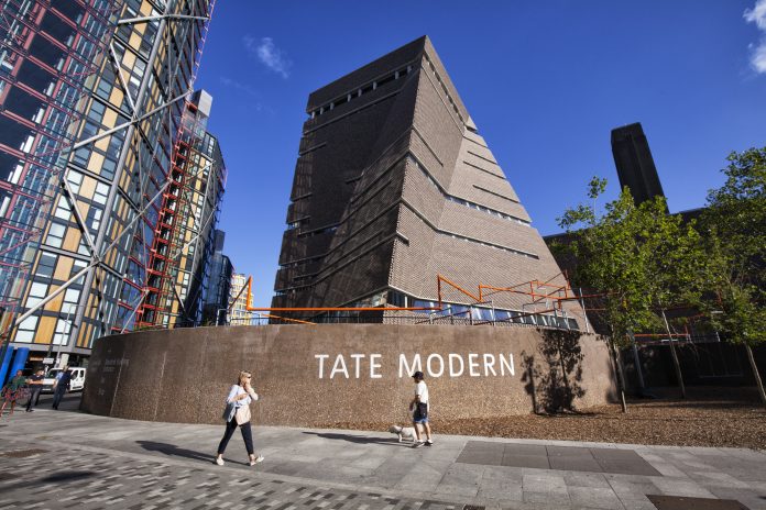 People walking by Tate Modern, an art gallery in south bank of London on a summer morning