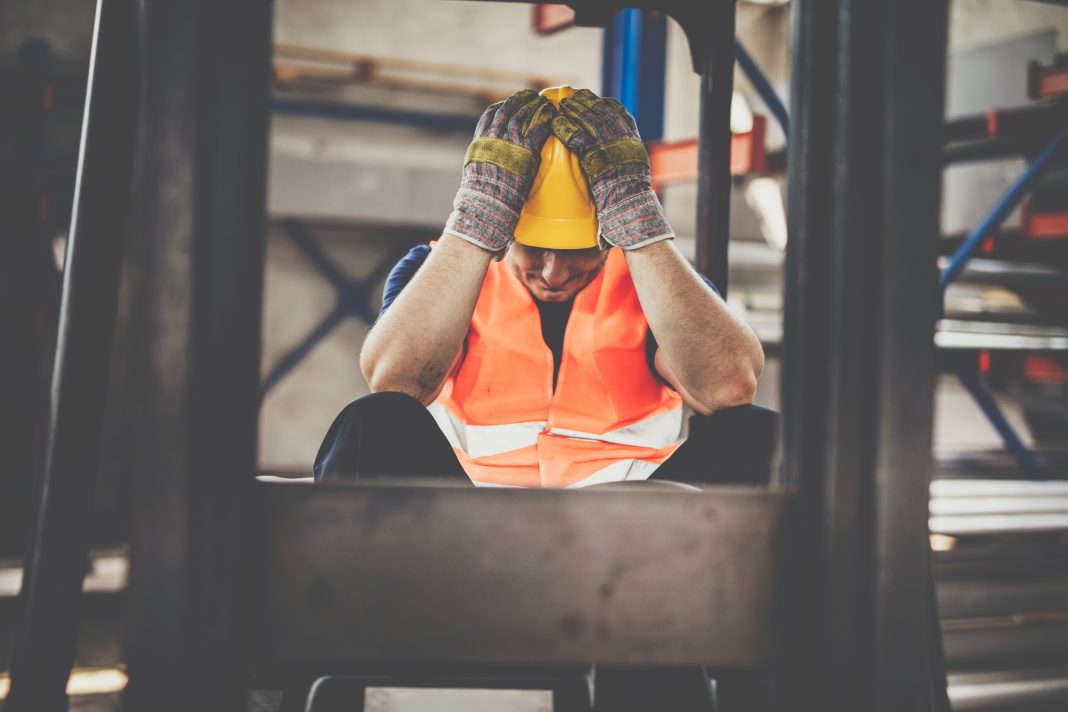 Forklift driver feeling frustrated while working in aluminum mill, representing mental health in construction