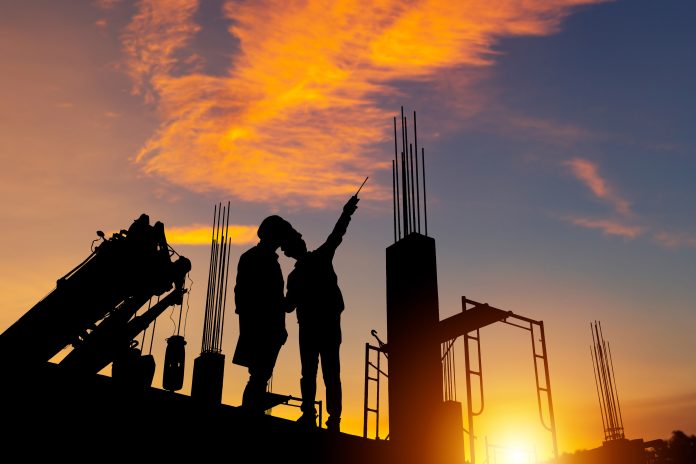 Silhouette of Engineer and worker checking project at building site background, construction site at sunset in evening time on an article about Jason Howden