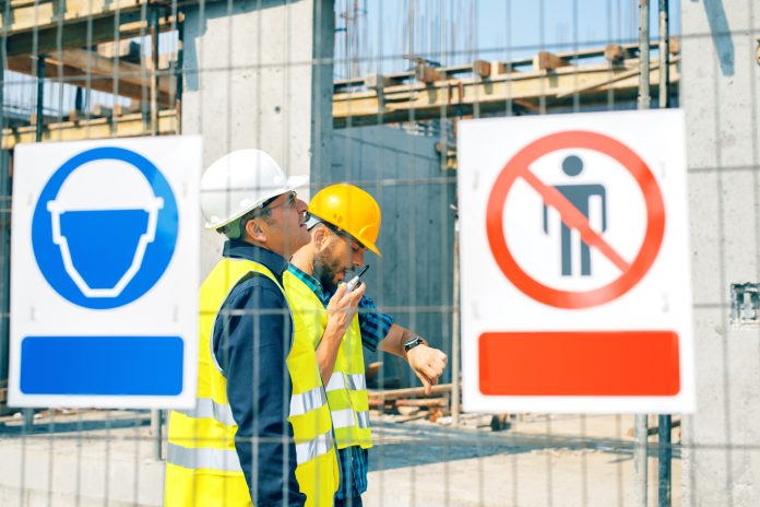 Engineer and construction site manager dealing with blueprints and projects. Construction site warning signs