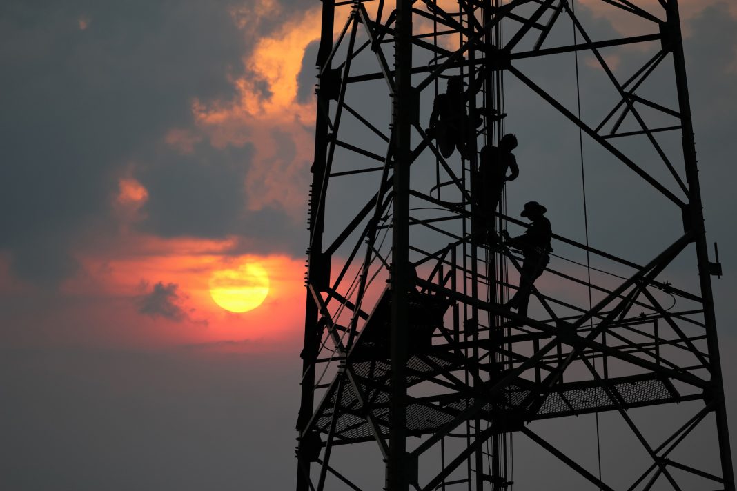 Workers are climbing to repair the telecommunication tower or poles, in the evening to represent Adastra Acess falling into administration