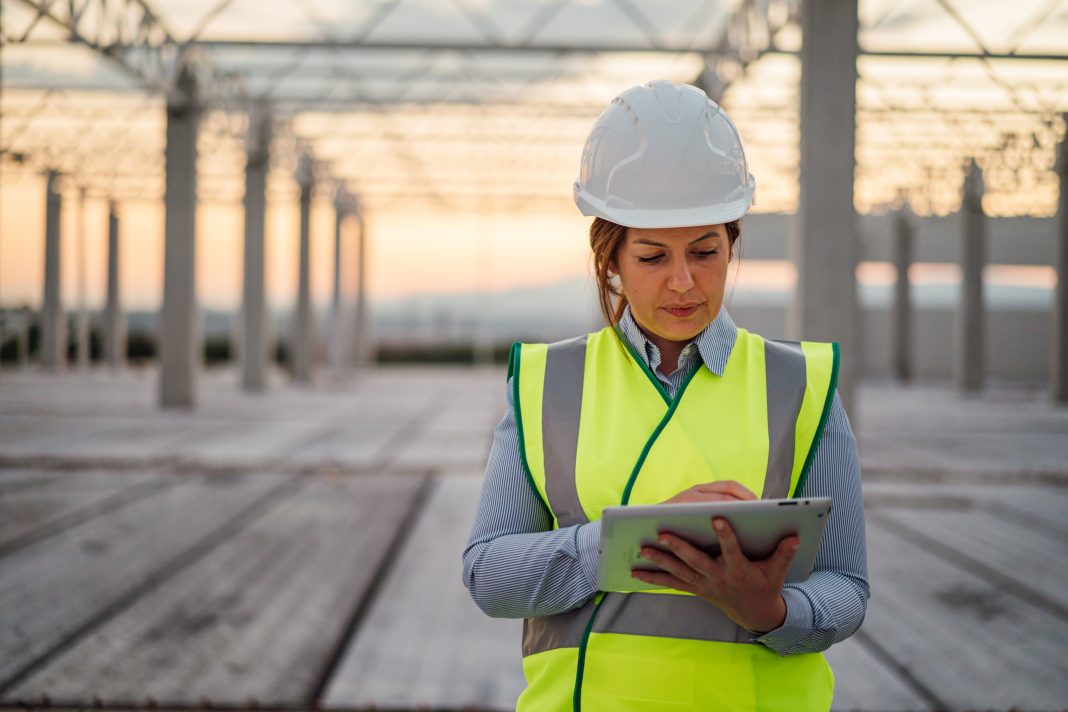 Female construction engineer is using digital tablet on the construction site, representing an environmental assessment