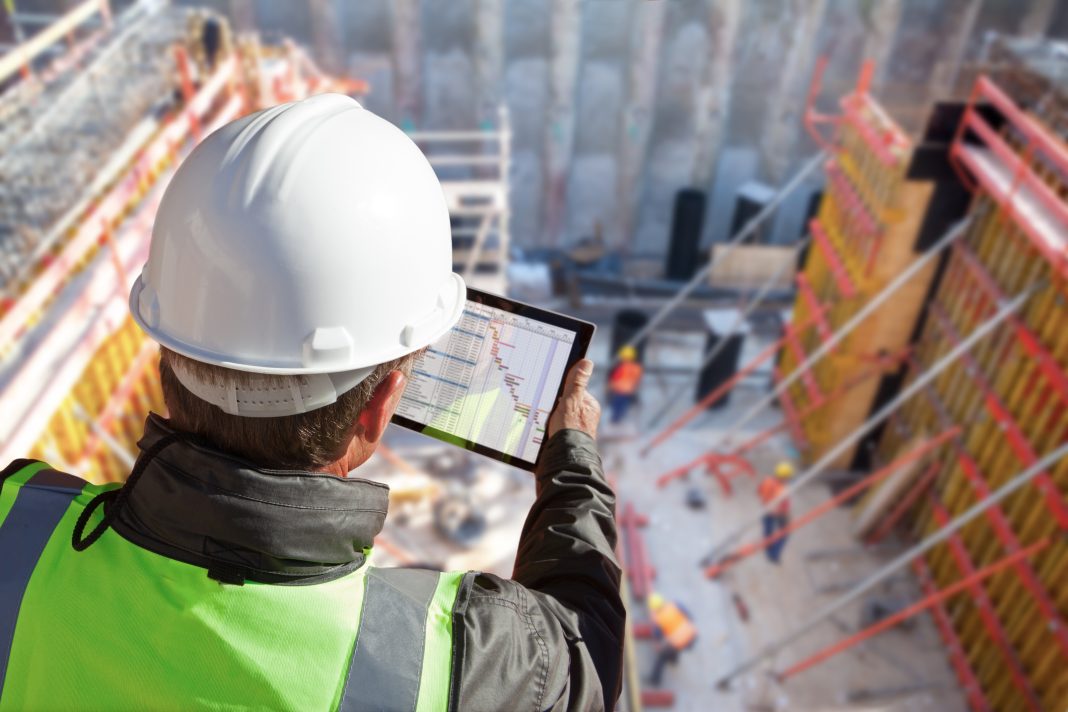 engineer architect construction worker on construction site with tablet computer top view of construction site with multinational worker