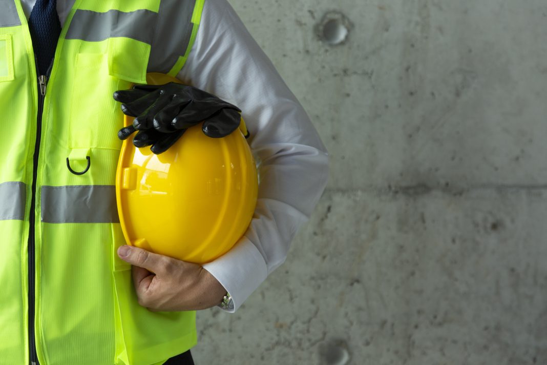 Portrait of Construction worker holding yellow helmet close up