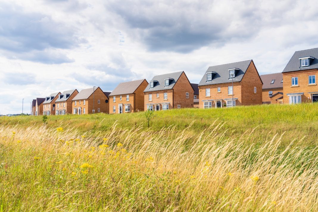 A view across meadow grass to a new build housing estate near Milton Keynes, England, representing Gove's plan to Relax planning rules