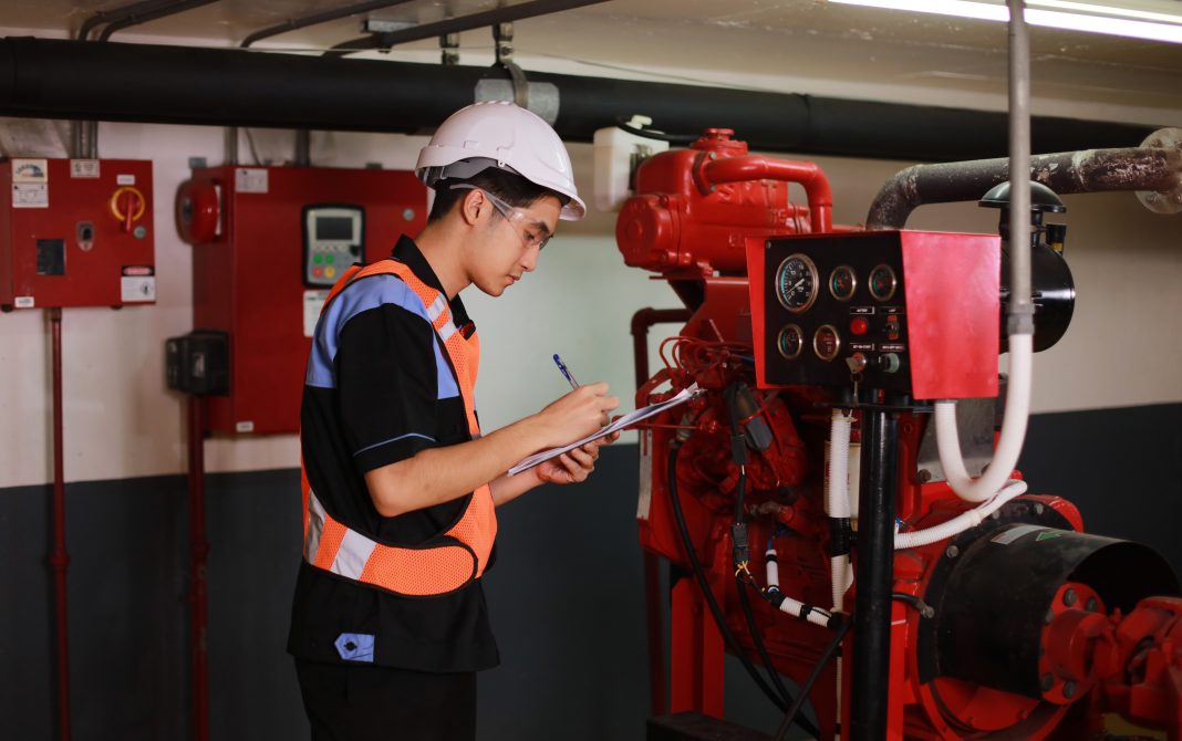 Young engineer check fire suppression system at conrol room of factoryYoung engineer check fire suppression system in control room of factory , daily check job of maintenance technician, representing fire safety specifications