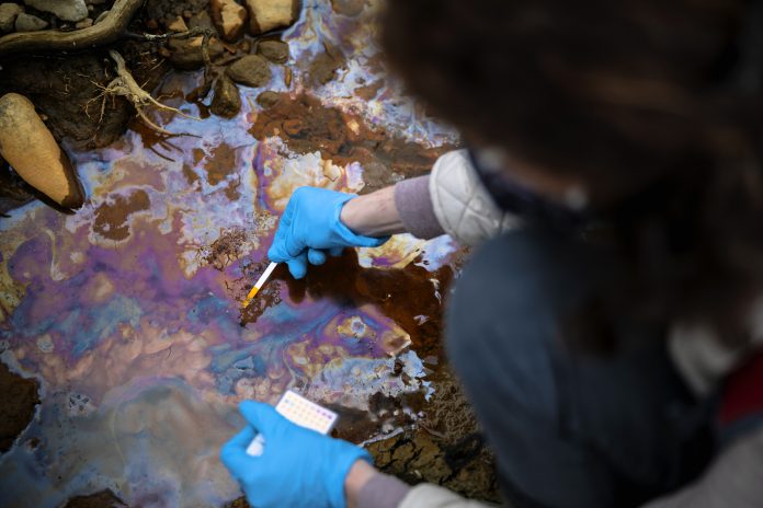 Measuring PH levels of Contaminated Water With Chemicals by an Expert, representing potentially unlimited fines for environmental polluters