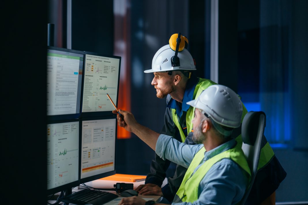 Group of operators control process on product line uses industry 4.0 and digital technology on modern factory. Two engineers follow assembly process uses SCADA system which AI technology and UI, representing the potential of construction data and technology