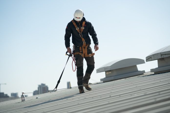 Construction worker wearing safety fastening on roof