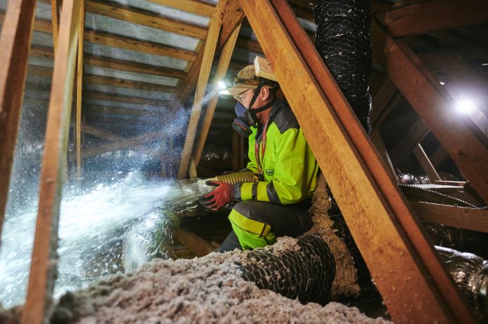 Worker installing insulation in loft