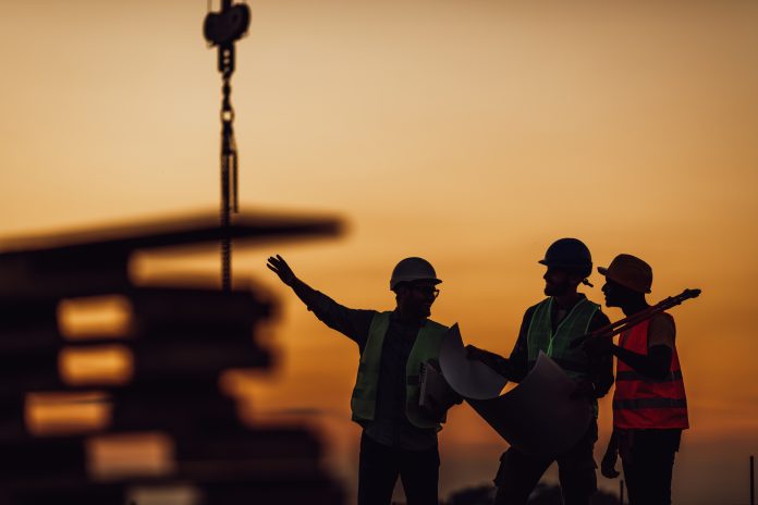 Stay ahead of 2023’s challenges with the Imerso Construction Playbook Silhouette of Survey Engineer and construction team working at site over blurred industry background with Light fair Film Grain effect